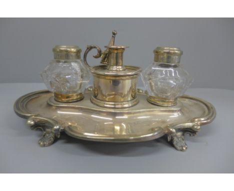 A silver plated ink stand with two glass  inkwells and a small chamber stick, with engraving dated 1856, 26cm 