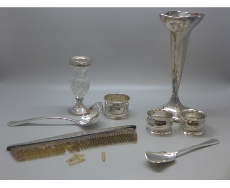 A silver vase, three silver napkin rings, a small silver ladle, silver sugar spade, silver top comb and silver rimmed glass v