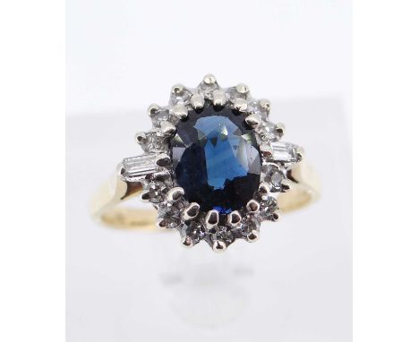 18CT GOLD SAPPHIRE &amp; DIAMOND CLUSTER RING, the central sapphire (7 x 6mms) surrounded by fourteen round and two baguette 