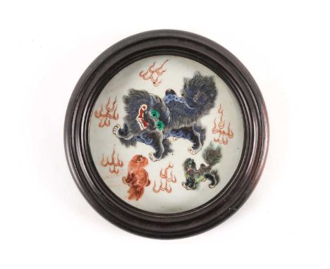 A Chinese porcelain circular plaque, Qing, 19th century, painted with a Buddhist lion and two pups, amidst flames, 17.5cm dia