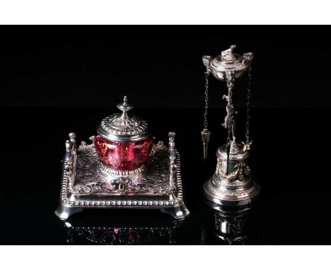 A Victorian silver plated inkwell with a square base and cranberry glass reservoir with bow pen rests and hinged cover. 18cm 