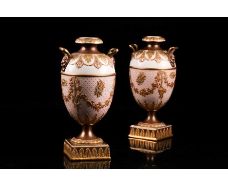 A pair of early 20th century Wedgwood Etruria,two-handled classical, porcelain urns with raised gilt oak leaf and anthemion d