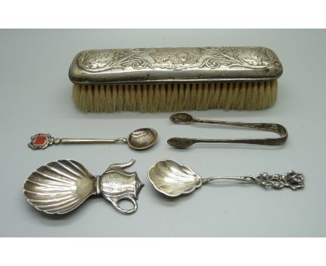 A silver tea caddy spoon, a pair of silver sugar bows, a silver backed brush and two spoons 