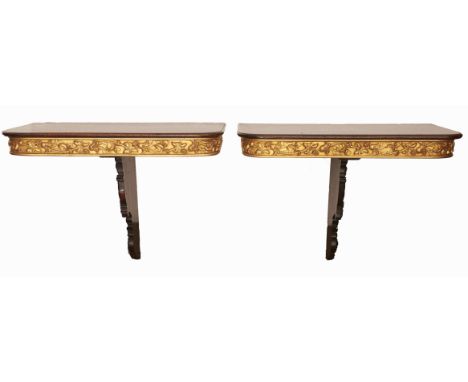 A pair of parcel gilt mahogany console tables, 20th c incorporating 19th c elements, with crisply carved leaf and scroll brac
