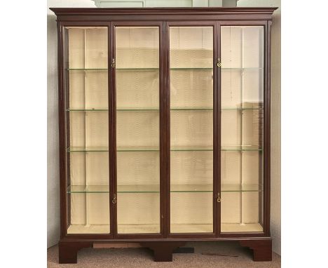 A mahogany showroom cabinet, early 20th c, enclosed by two pairs of glazed doors with brass ring catches, on bracket feet, 21