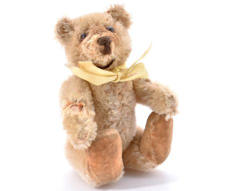 A Steiff miniature teddy bear, c1930's, of pale golden mohair with brown stitched snout  Bald patch on right arm showing stra