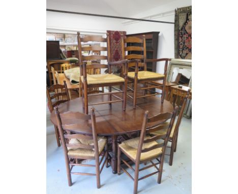 An antique style oak gate leg table with 8 ladder back chairs including two carvers with rush seats - Table height 74cm x 152