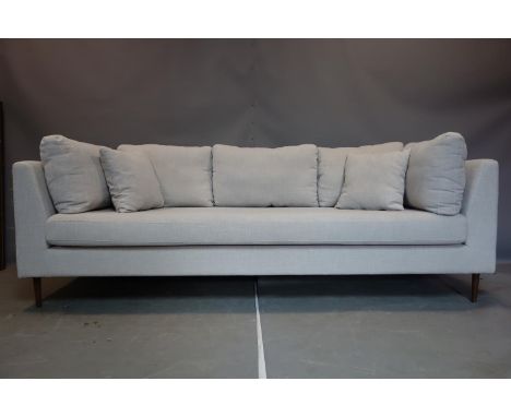 A contemporary three seater sofa with grey linen upholstery, raised on tapered teak legs 