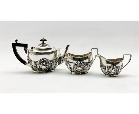 Edwardian bachelors silver three piece tea set of oval design with embossed decoration, the tea pot with blackwood handle and