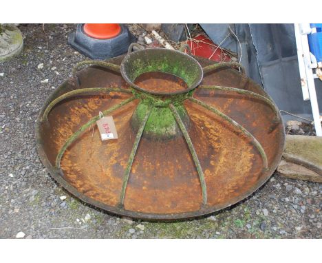 A circular cast iron pig trough, 3' diameter, some cracks.