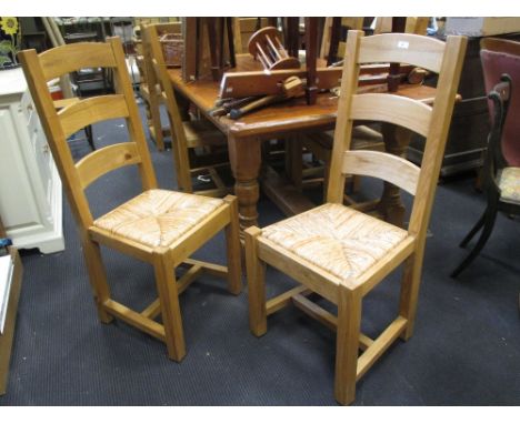 A modern pine dining table, 77 x 178 x 104cm, and six ladder back oak chairs with rush seats  