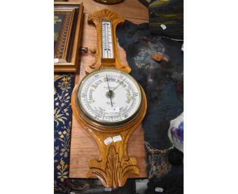 An early 20th century light oak aneroid bango/wheel barometer, marked for T &amp; E Rhodes, Kendal (loose glass)