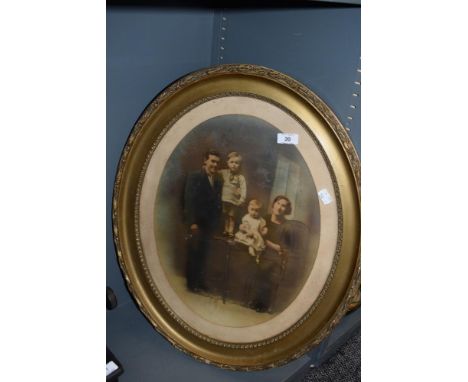 An early 20th century family photo portrait in an ornate oval gilt and gesso frame.