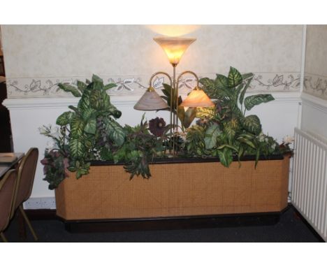 A canted oblong caned planter, housing a variety of artificial plants and centred by a three branch light fitting with marble