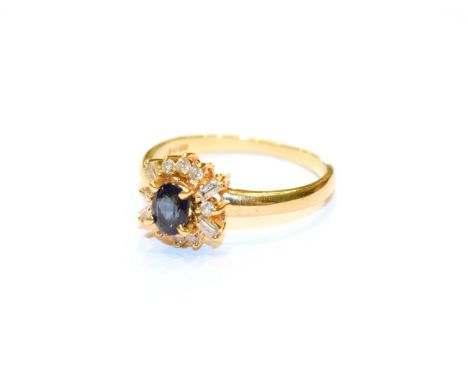 An 18 carat gold sapphire and diamond cluster ring, the oval cut sapphire within a border of round brilliant cut and tapered 