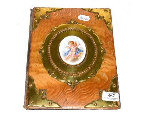 A Victorian brass mounted desk blotter, oblong and with brass mounted corners, the centre set with a porcelain plaque painted