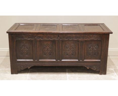 A large 18th century carved oak coffer, with a four panel hinged cover, the two central panels carved with geometric lozenge 