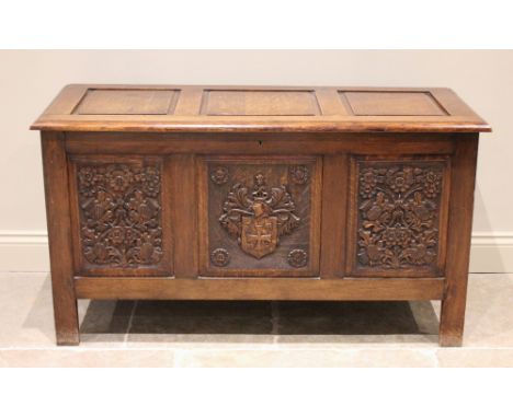 A 17th century style oak coffer, mid 20th century, the three panel hinged top over a central panel carved with a heraldic shi