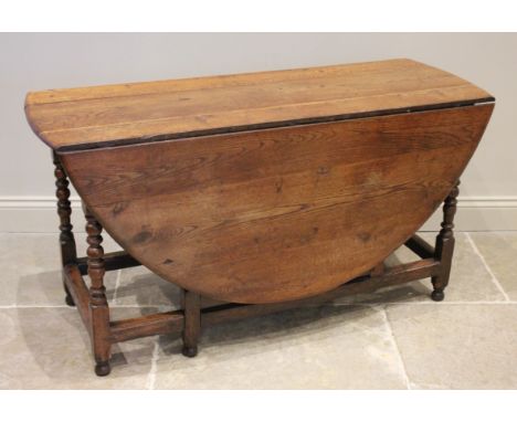 An 18th/19th century oak drop leaf dining table, the oval top raised upon bobbin turned and block supports united by peripher