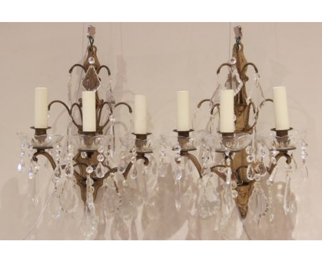 A pair of French gilt metal three branch wall light fittings, early 20th century, the shaped back plates with two tiers of ha