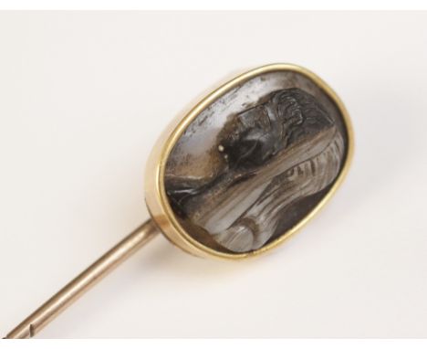 A 19th century carved hardstone cameo set stick pin, the oval shaped cameo carved with the profile of a veiled figure facing 