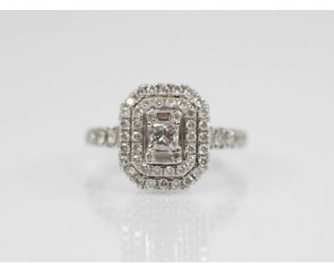 A diamond 18ct cluster ring, comprising a central princess cut diamond weighing 0.25 carats, flanked by baguette cut and bril
