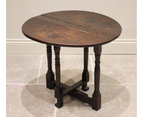 An 18th century and later narrow oak drop leaf occasional table, the circular top raised upon ring turned tapering supports a