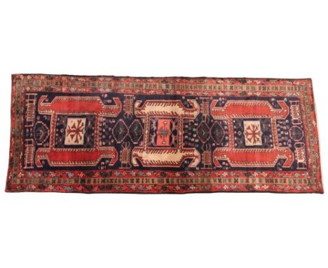 An Iranian Meshkin type wool runner, in predominately red, blue and ivory colourways, the three central geometric medallions 