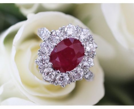 A ruby and diamond cluster ring, the central oval mixed cut ruby weighing 2.10 carats (measuring 8.8mm x 6.9mm x 3.5mm), with