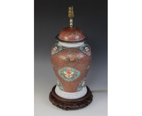 A Chinese porcelain Rouge de Fer lamp base on stand, of baluster form, decorated with floral panels against a red ground with