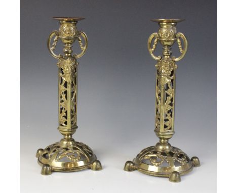 A pair of Victorian brass candlesticks, each cast with arabesques and masks above a domed and pierced base, impressed sun mar