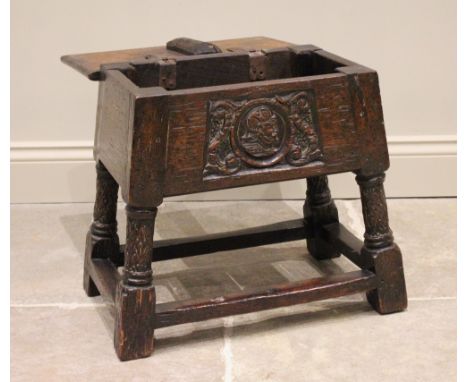 A 17th century and later hinged oak joint stool, the rectangular moulded hinged top above a front panel carved with a Romayne