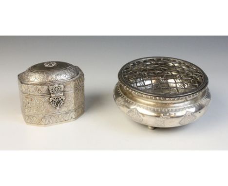 A silver coloured tea caddy, of faceted form with hinged cover and catch, elaborately engraved with scrolling decoration, 7.8