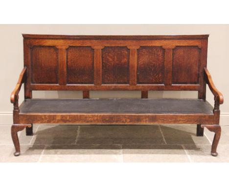 A George III oak five panel settle, the moulded back rail above five invert moulded panels and a later board seat, enclosed b