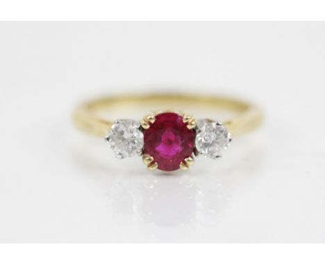 A ruby and diamond three stone ring, the central oval mixed cut ruby (untested) measuring 5.6mm L x 4.5mm W x 3mm D, with a r