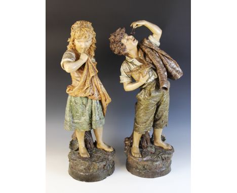 A pair of early 20th century continental patinated plaster figures, modelled as a boy holding a basket of fruit and a girl ho