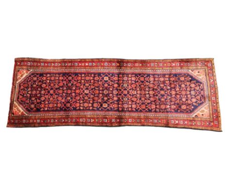 An Iranian wool runner, in blue and red colourways, the central blue field overlaid with a foliate and lattice design, within