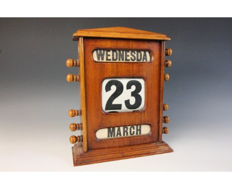 An early 20th century walnut cased perpetual roller desk calendar, of architectural form, the roller displays with turned han