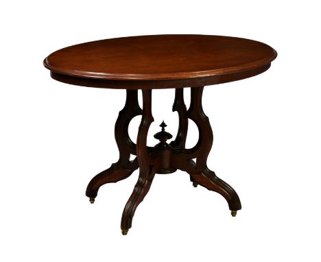 A late Victorian oval walnut centre table, the moulded top raised on four shaped supports issuing from a central urn finial, 