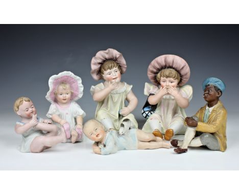 A collection of early 20th century bisque piano dolls, comprising of a pair of large infant girls, the tallest, 7¾in. (19.8cm