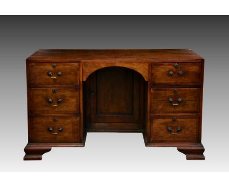 An early Georgian style walnut double pedestal desk, c.1920, the cross banded top over an arched kneehole with inset panelled