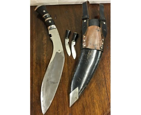 A Kukri with leather scabbard and accompanying knives, probably 20th century, horn handle with metal mounts, polished steel b