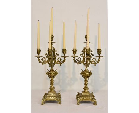 A pair of modern cast brass neoclassical style four branch table candelabra, having scrolling foliate and lion mask decoratio