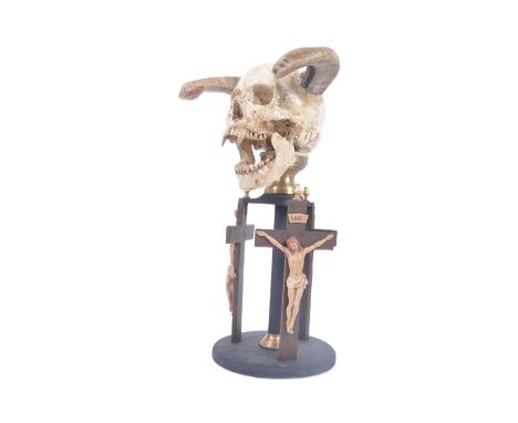 A contemporary demonic skull head, with rams horns and fangs to the head supports by an ebonised stand adorned with three cru