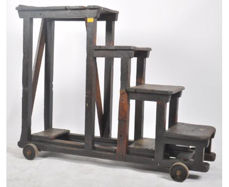 A large early 20th century stained pine wood industrial railway / mill steps ladder on wheels. The trolley made of four steps