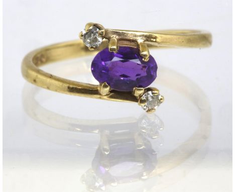 Amethyst and paste ring, central oval cut amethyst in a crossover design with two smaller colourless paste stones either side