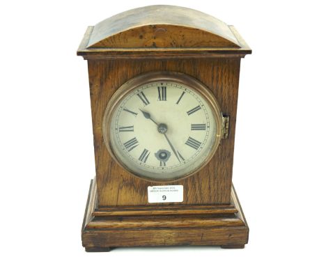 A stained oak cased mantel clock. The painted dial with Roman numerals denoting hours, 25cm high