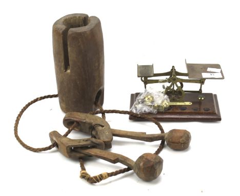 A letter scale and weights together with a wooden cow bell. The scales mounted on a wooden base