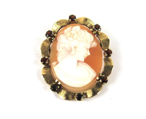 A vintage gold, garnet and shell cameo oval brooch. The cameo depicting an unknown female head and shoulders bust, claw set w