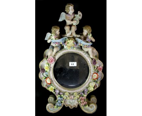 A large German porcelain table mirror decorated with cherubs, H. 57cm  (some restoration to the back).